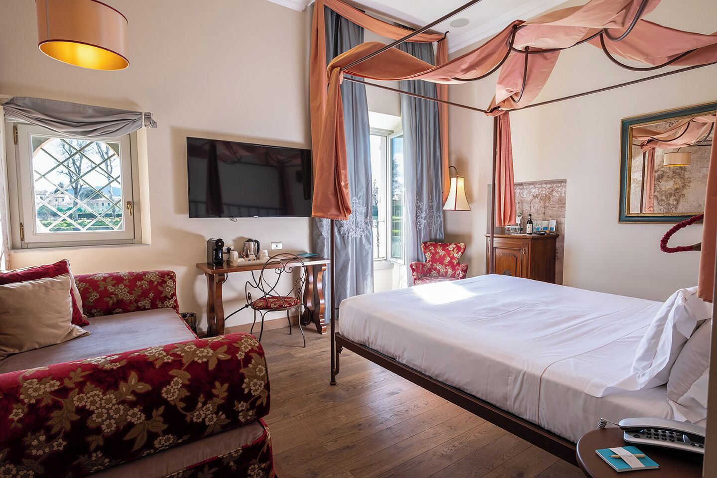 A hotel room with a bed, a desk, a television, a window, and a chair.