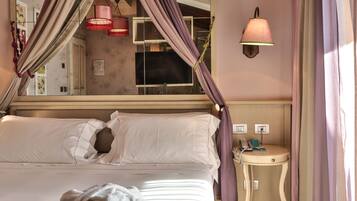 A bed with a canopy, a bedside table with a phone, and a wall-mounted light fixture.