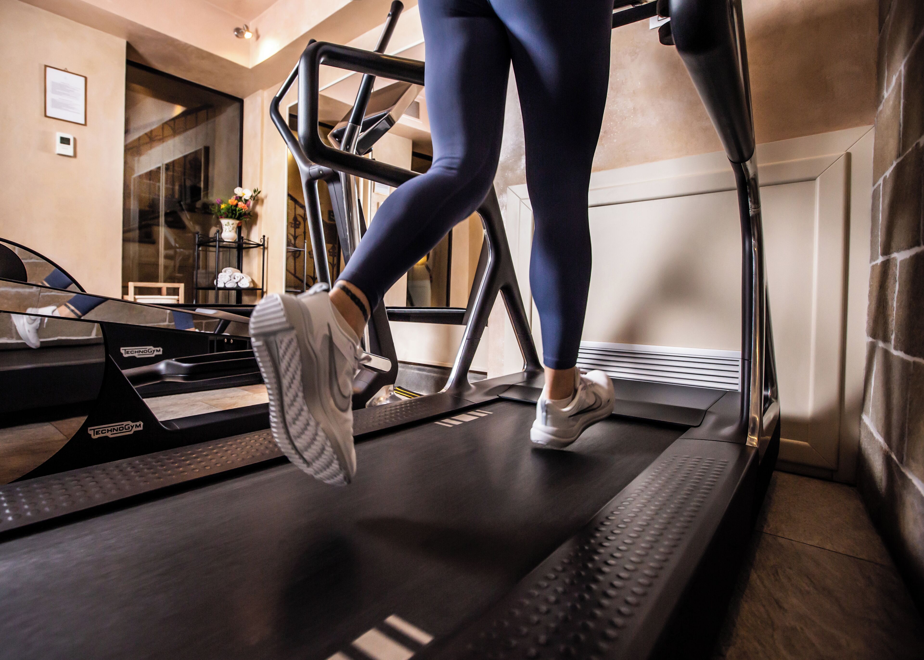 A treadmill in a room with a mirror, a window, and a door.