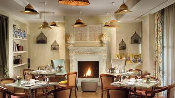Comedor con chimenea, sillas de madera y lámparas colgantes.