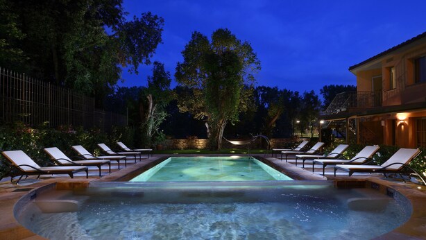A swimming pool with lounge chairs and a stone wall.