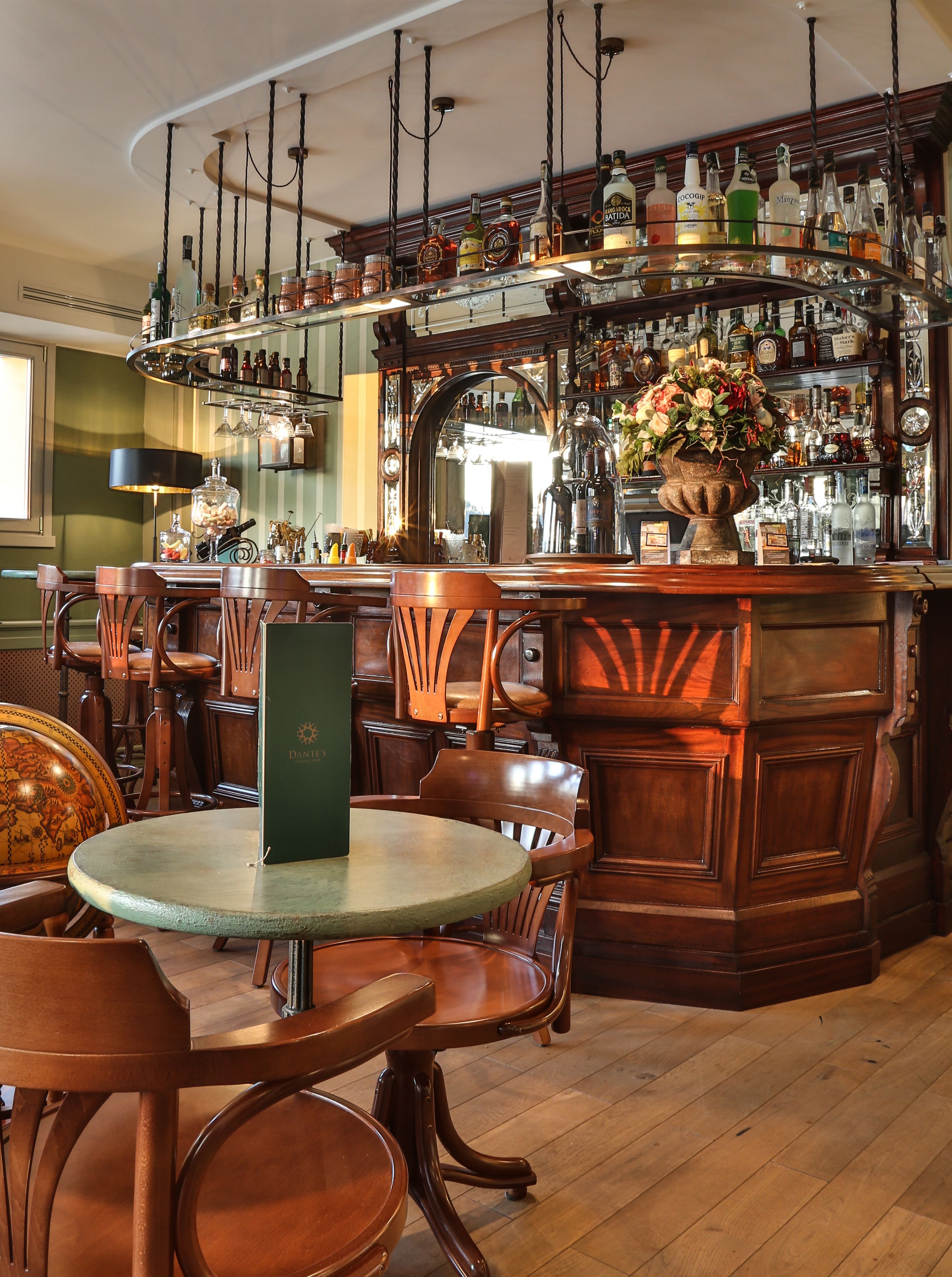 Eine Bar mit Holzkulturen, einem runden Tisch und einer Auswahl an Flaschen und Gläsern auf Regalen.