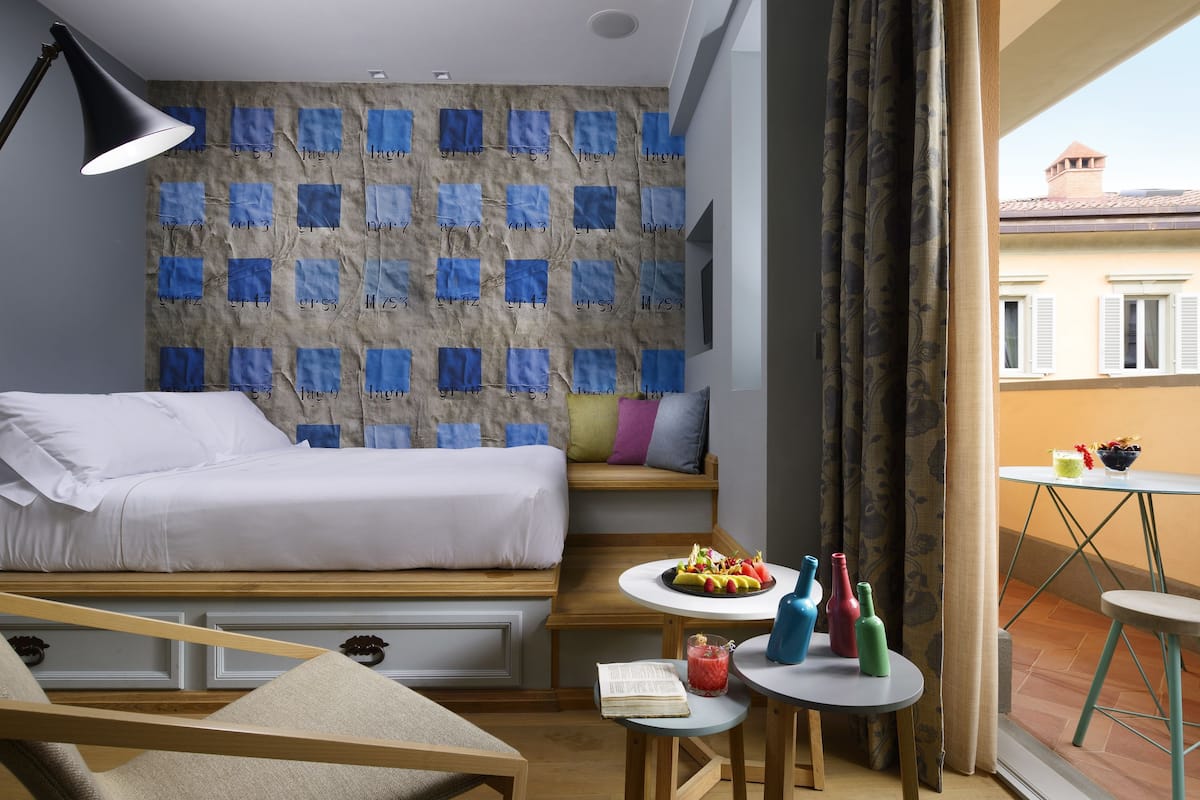 A bedroom with a bed, bedside tables, a lamp, a window with curtains, and a view of the outside.