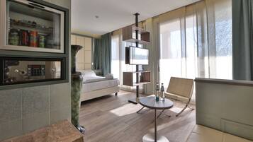 Una habitación de hotel moderna con una cama, una mesita redonda pequeña, un sofá, un televisor integrado y un minibar.