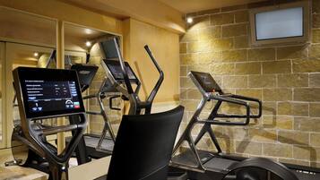 Un gimnasio con equipo de ejercicio, incluyendo cintas de correr y una máquina elíptica, con pantalla digital para registrar entrenamientos.