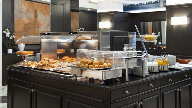 Ein reichhaltiges Buffet mit verschiedenen Speisen, einer Kaffeestation und einer Wand mit Dekoration.