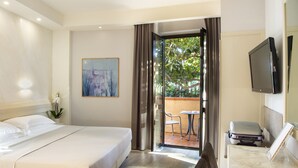Ein Hotelzimmer mit einem Bett, einem Schreibtisch mit Koffer, einem Fernseher und Blick auf Grün durch das Fenster.