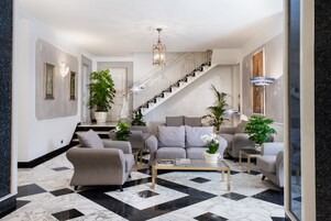 A spacious living area with a large sofa set, a coffee table, and a staircase leading to another level.