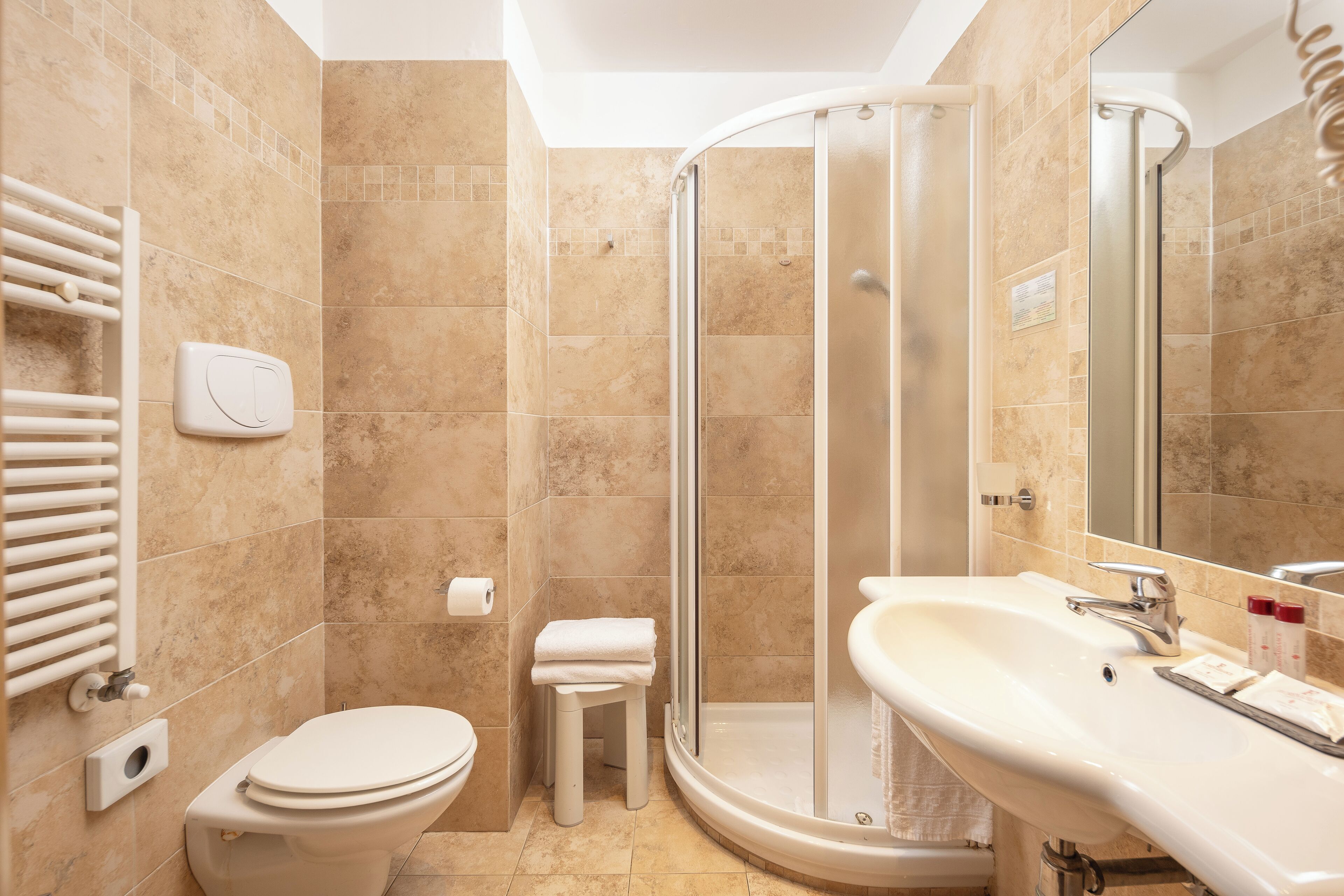Une salle de bain équipée d’un WC, d’un lavabo, d’une douche et d’un porte-serviettes.