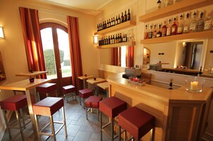 A bar area with multiple stools, a counter with bottles, and a view through a window.