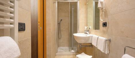 A modern bathroom with a glass-enclosed shower, a sink with a mirror, and a bathtub.