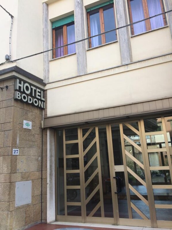 A hotel entrance with a sign reading "HOTEL BODONI" and the number "27" on the wall.