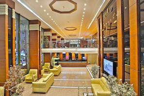 A spacious lobby with a high ceiling, multiple seating areas, and a large television screen. - Grand Madrid Hotel (Istanbul)