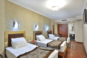 A hotel room with three beds, a bathroom, and a TV. - Grand Madrid Hotel (Istanbul)