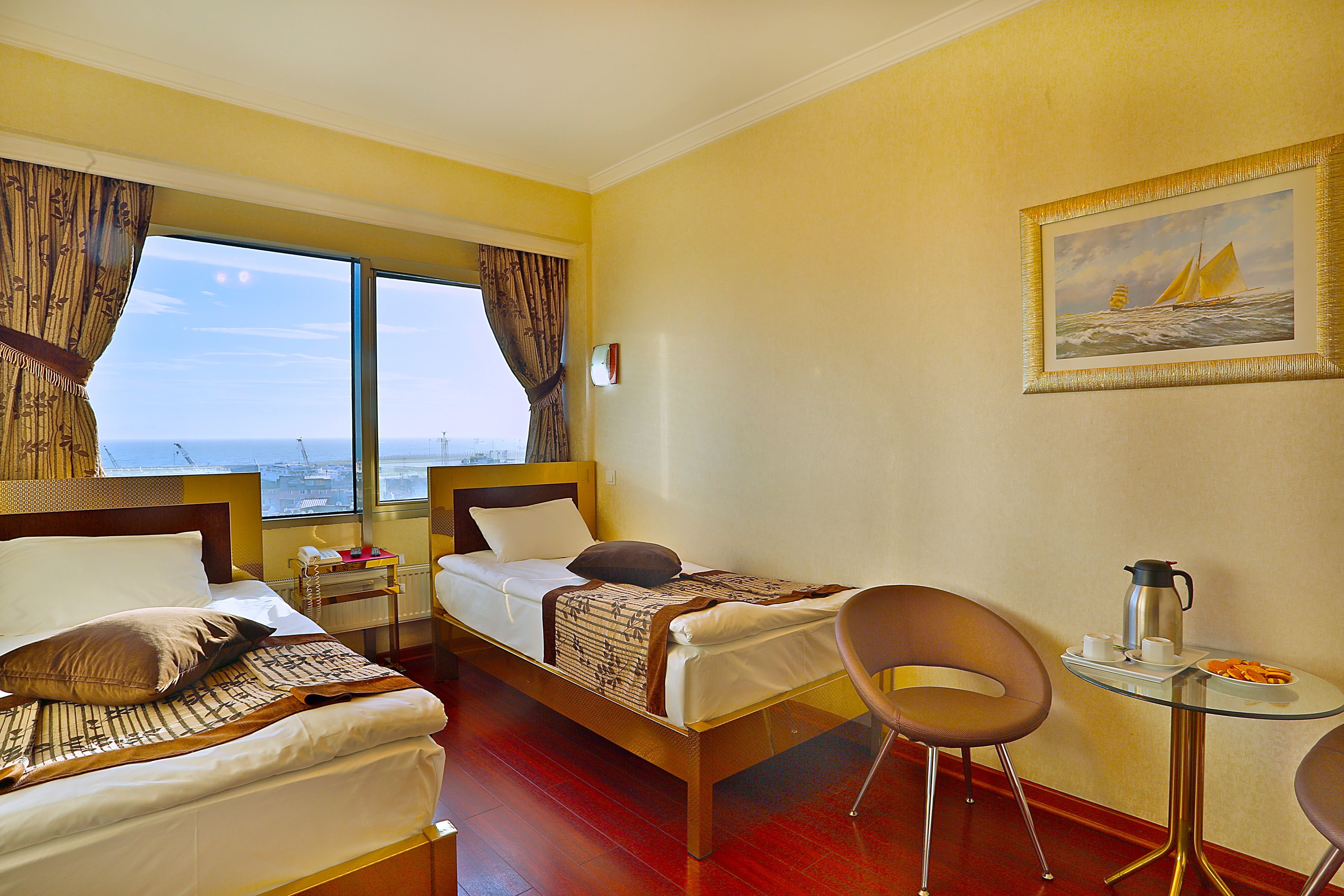 A hotel room with two beds, a small table with a coffee pot, and a chair.