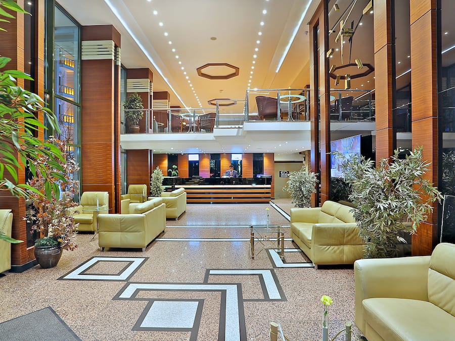 Un vestíbulo amplio con varias zonas de estar, una recepción y vistas al interior del edificio.
