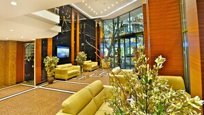 Un hall d’entrée moderne avec des canapés jaunes, un grand écran de télévision et un mur de verre donnant sur l’extérieur.