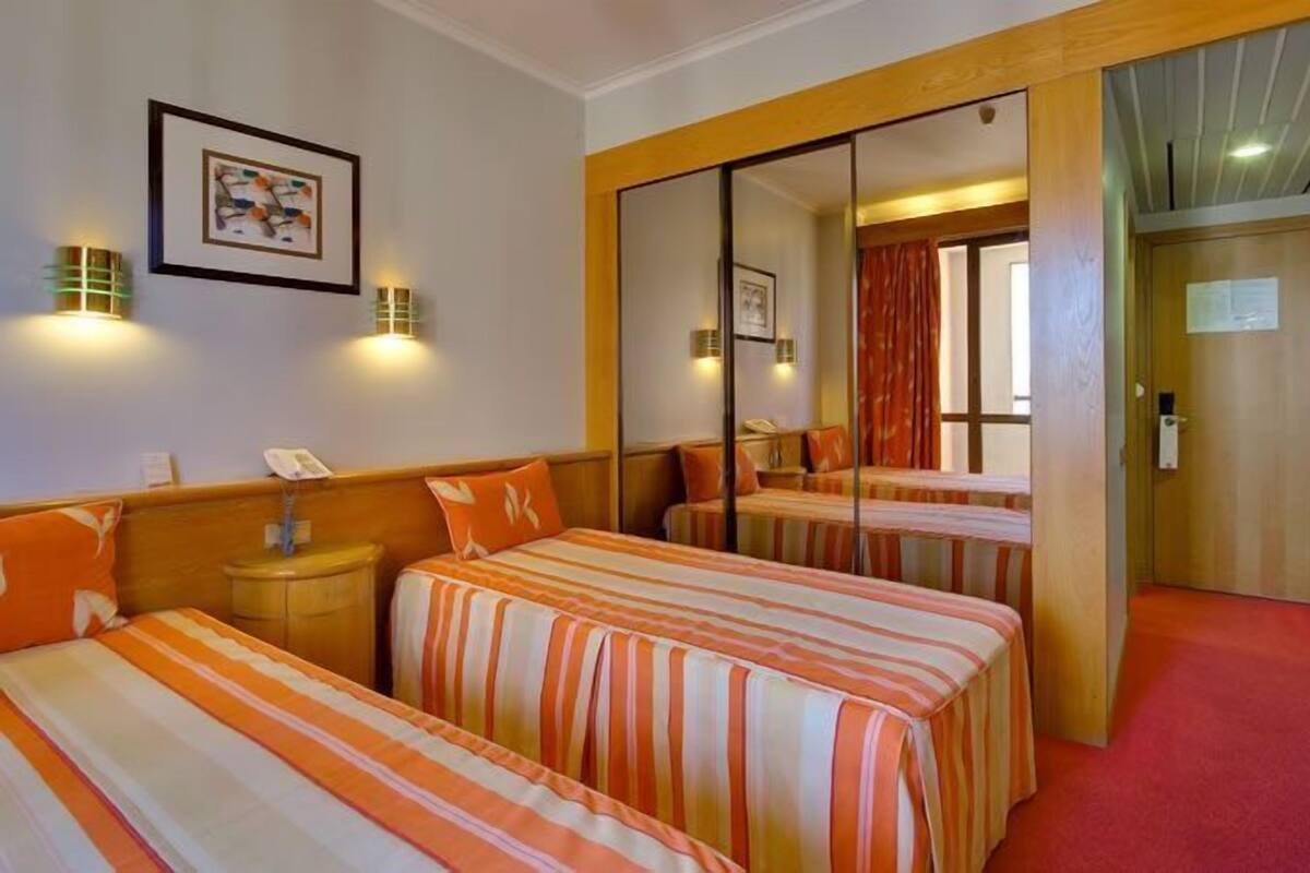 A hotel room with two beds, a large mirror, and a red carpet.