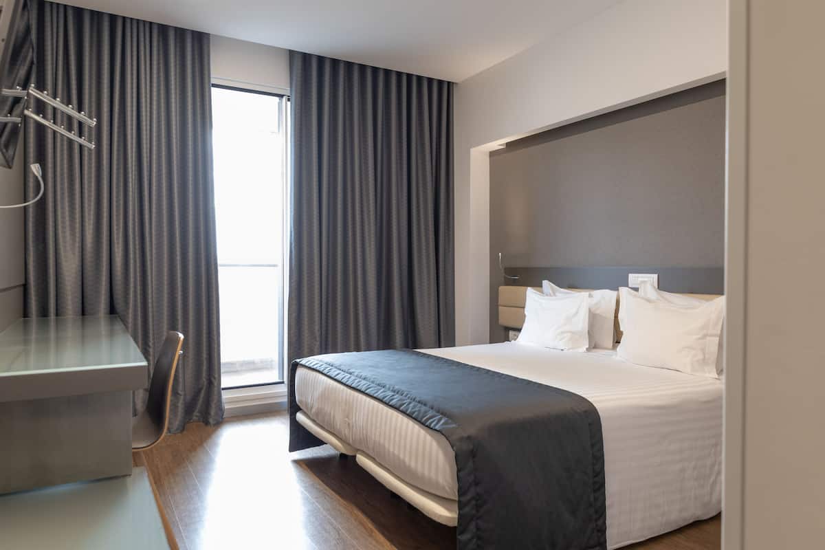 A hotel room with a bed, a desk, and a chair.