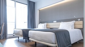 Une chambre d’hôtel moderne avec un grand lit, une table de chevet et une vue sur l’extérieur.