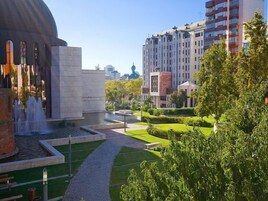Um edifício moderno com estrutura em cúpula, rodeado por um jardim bem cuidado e um caminho.