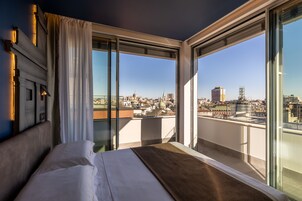 Una camera d'albergo con un letto grande, vista sulla città e un balcone con ringhiera.