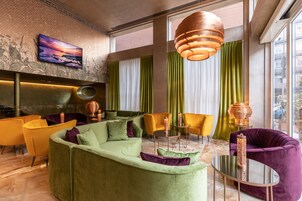 A modern living room with a green sofa, yellow chairs, and a round coffee table.