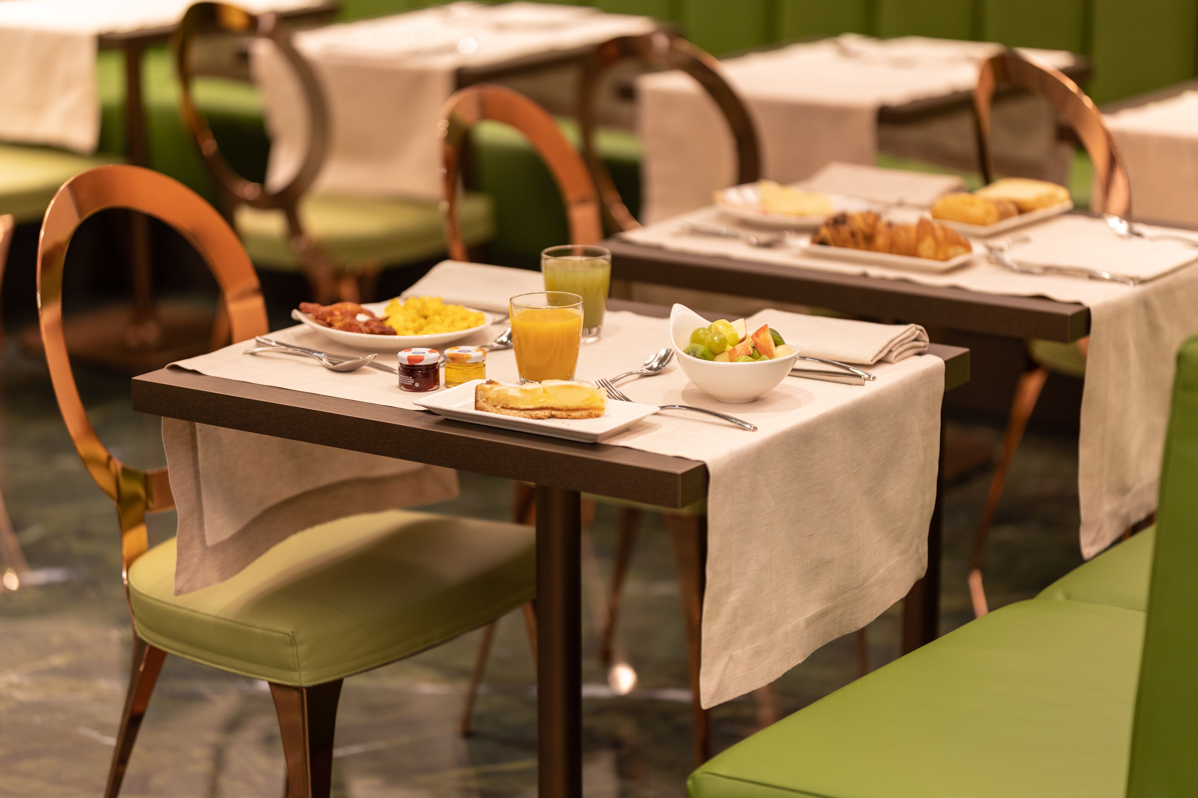 Une table mise pour le petit-déjeuner, avec des tables, des chaises et une variété d’aliments et de boissons pour le petit-déjeuner.