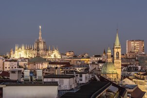 Paesaggio urbano con una cattedrale imponente e una torre dell'orologio, circondato da edifici moderni.