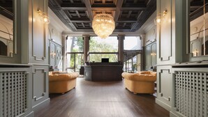 A spacious room with a large chandelier, wooden flooring, and two yellow armchairs. - Mokinba Hotels Montebianco (Milan)
