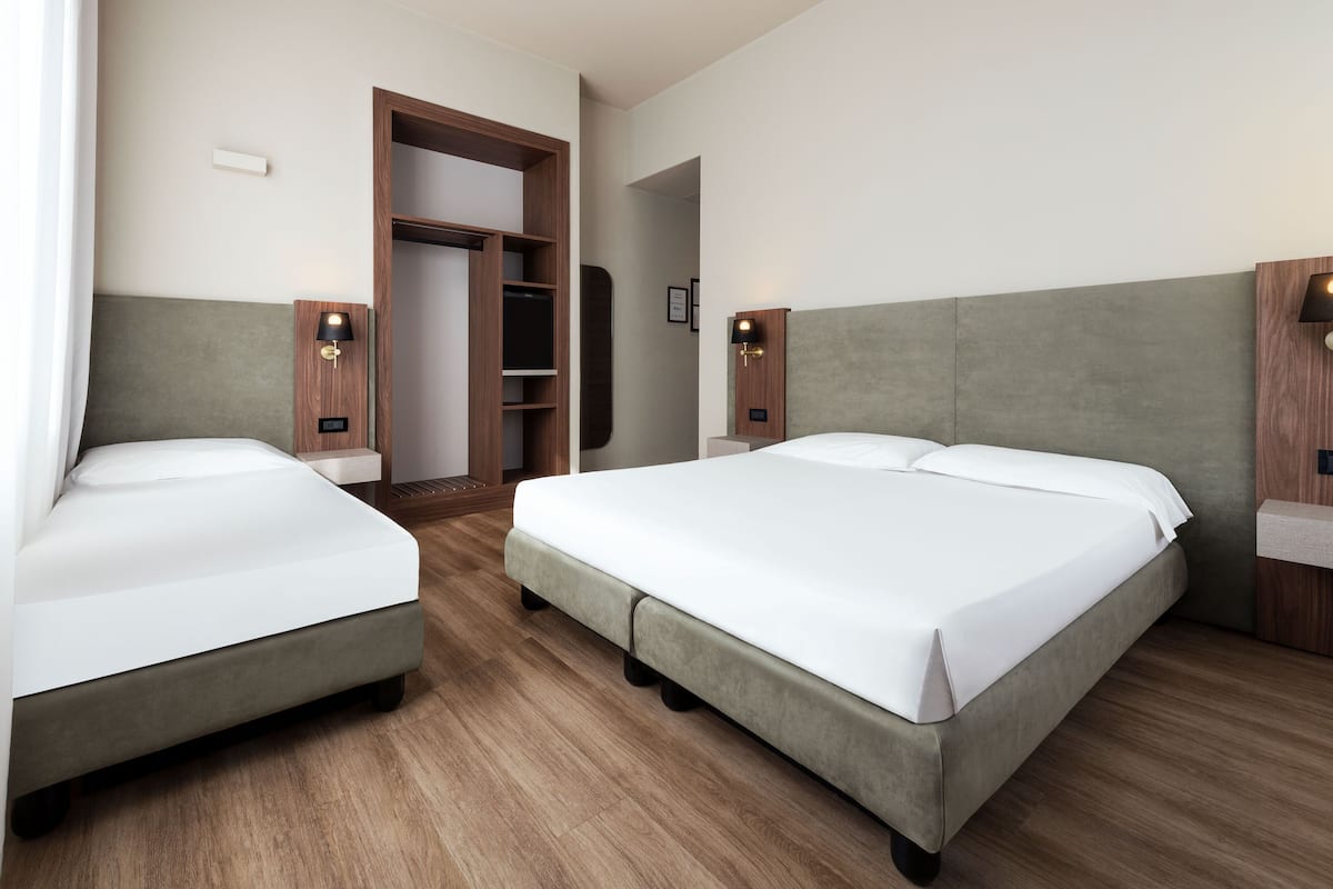 A hotel room with two beds, a wardrobe, and two bedside lamps.