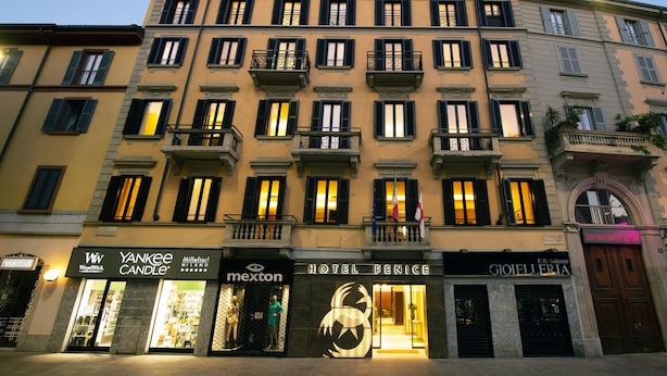 Un edificio de varios pisos con diversas tiendas, incluyendo una Macy's, una Mexton y un hotel llamado Hotel Fenice.