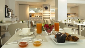Un desayuno con una mesa dispuesta para dos, que incluye un plato de comida, un bol de fruta y dos vasos de jugo de naranja.