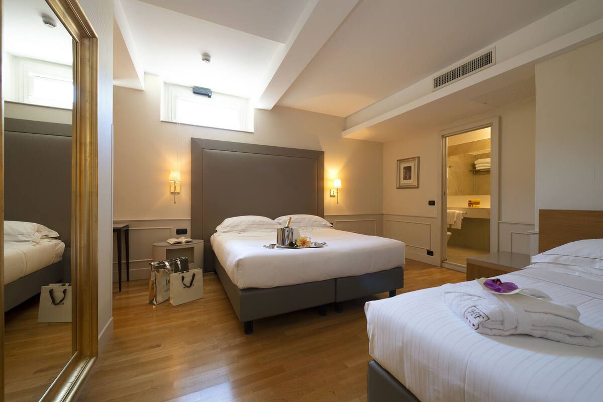 A hotel room with a large bed, a bedside table, a mirror, and a walk-in closet.