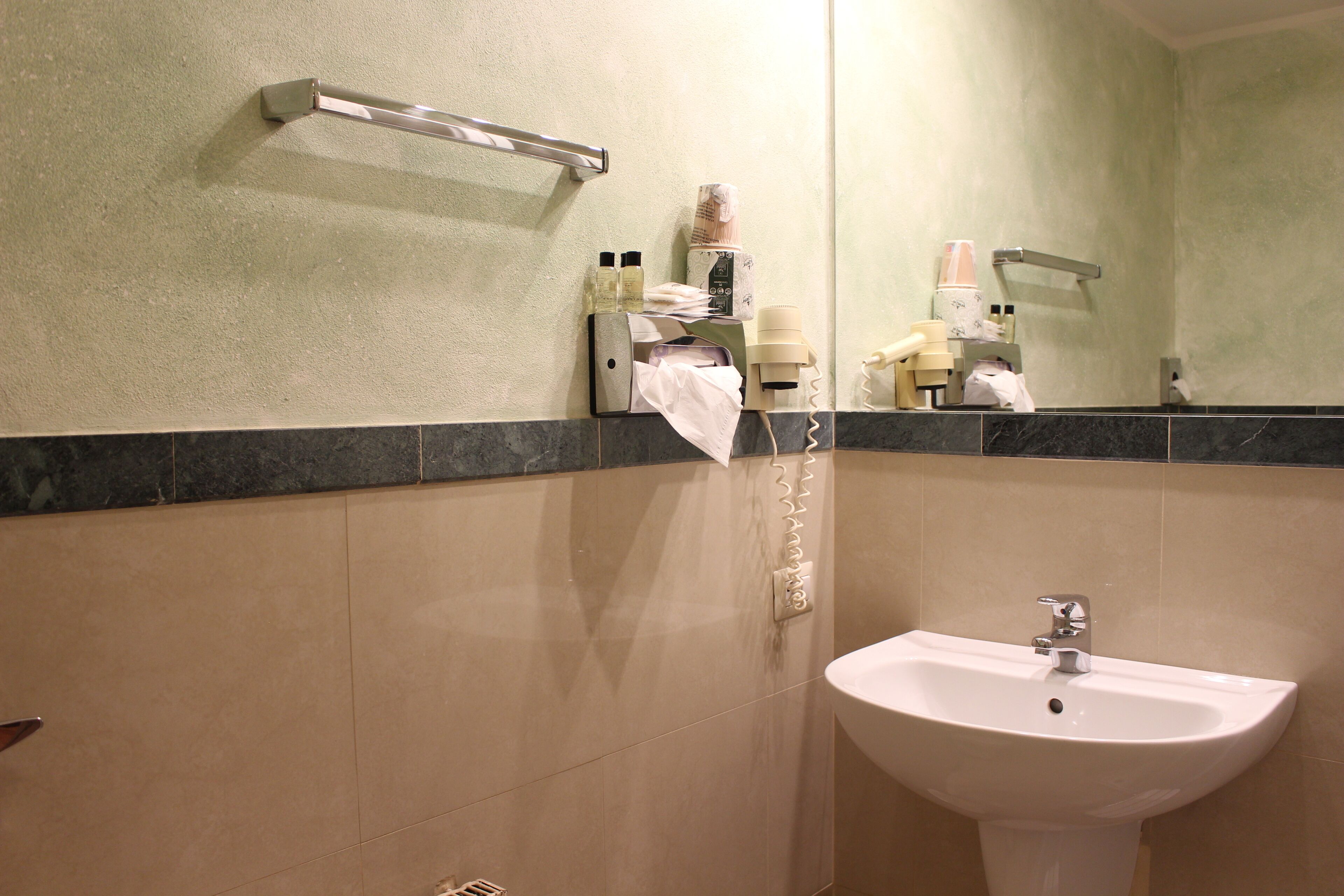 A bathroom with a sink, mirror, towel rack, and toiletries.