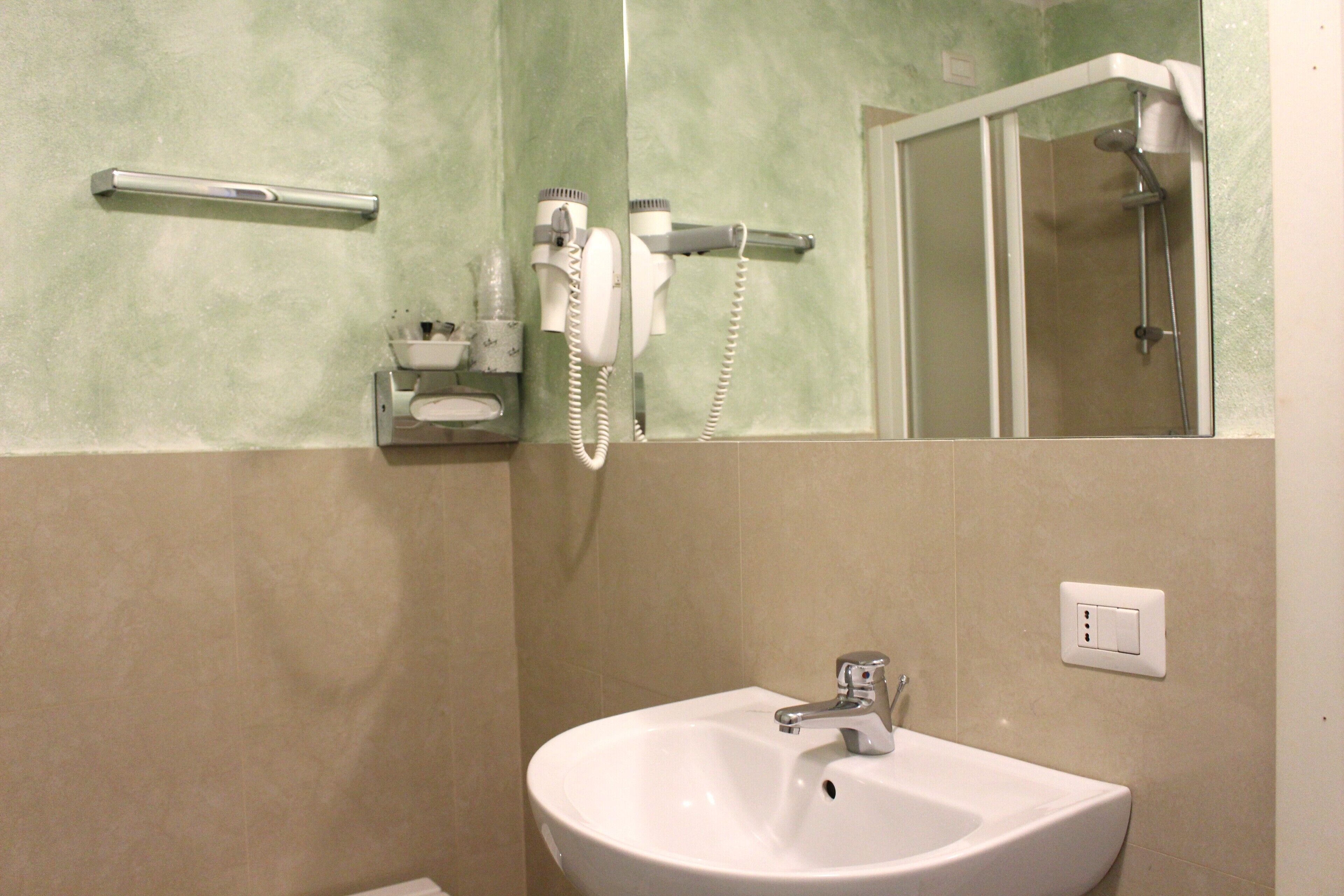 A bathroom with a sink, a hairdryer, and a mirror.