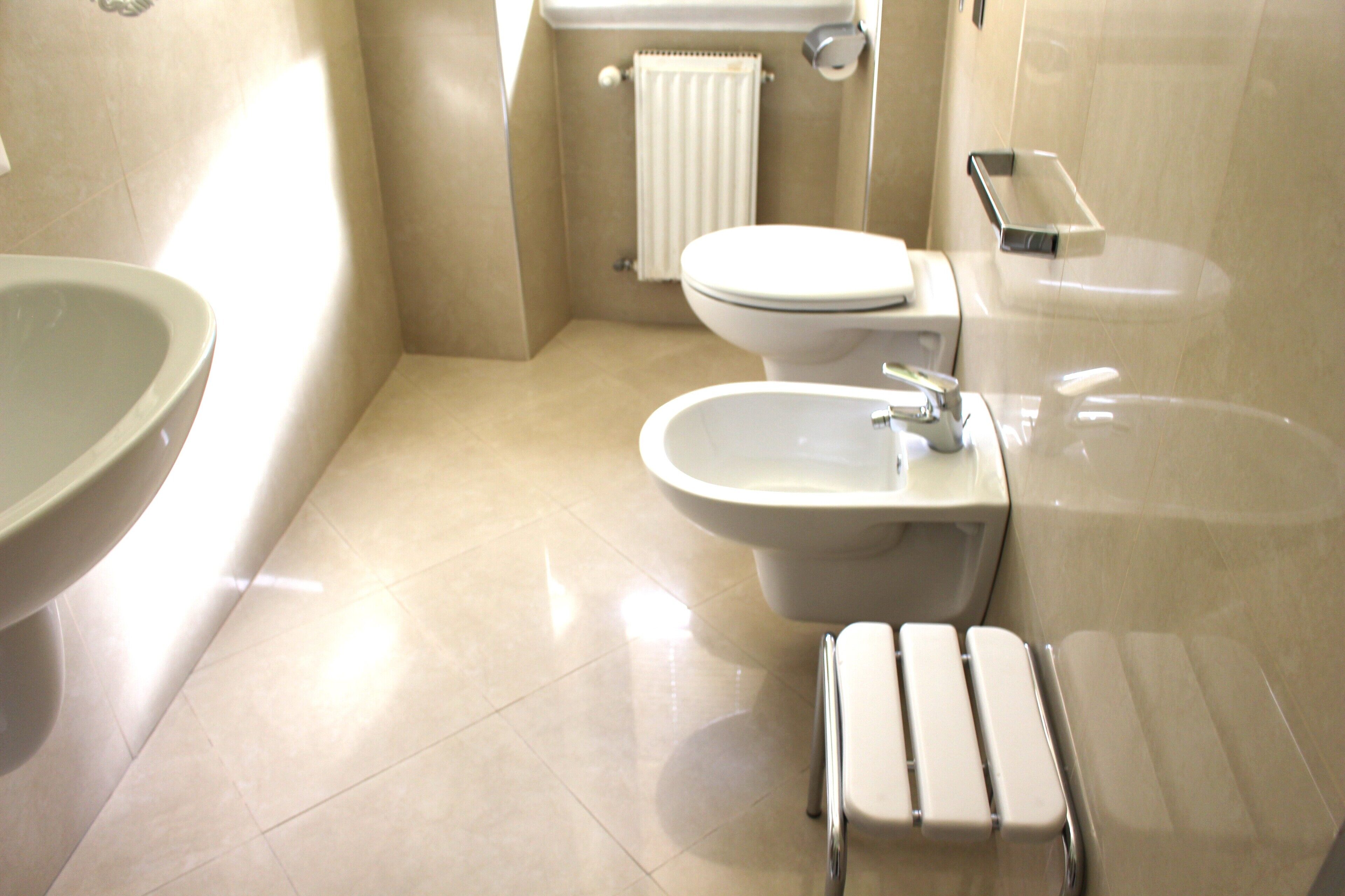 Un bagno con WC, bidet, lavandino e porta asciugamani.