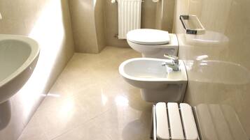 Un bagno con WC, bidet, lavandino e porta asciugamani.