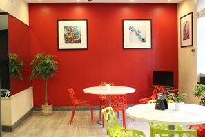 Relax in a stylish space with a round table, vibrant artwork, and a potted plant.