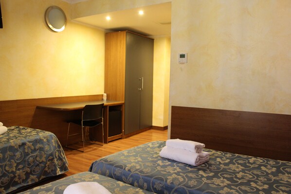 A hotel room with two beds, a desk, and a wardrobe.