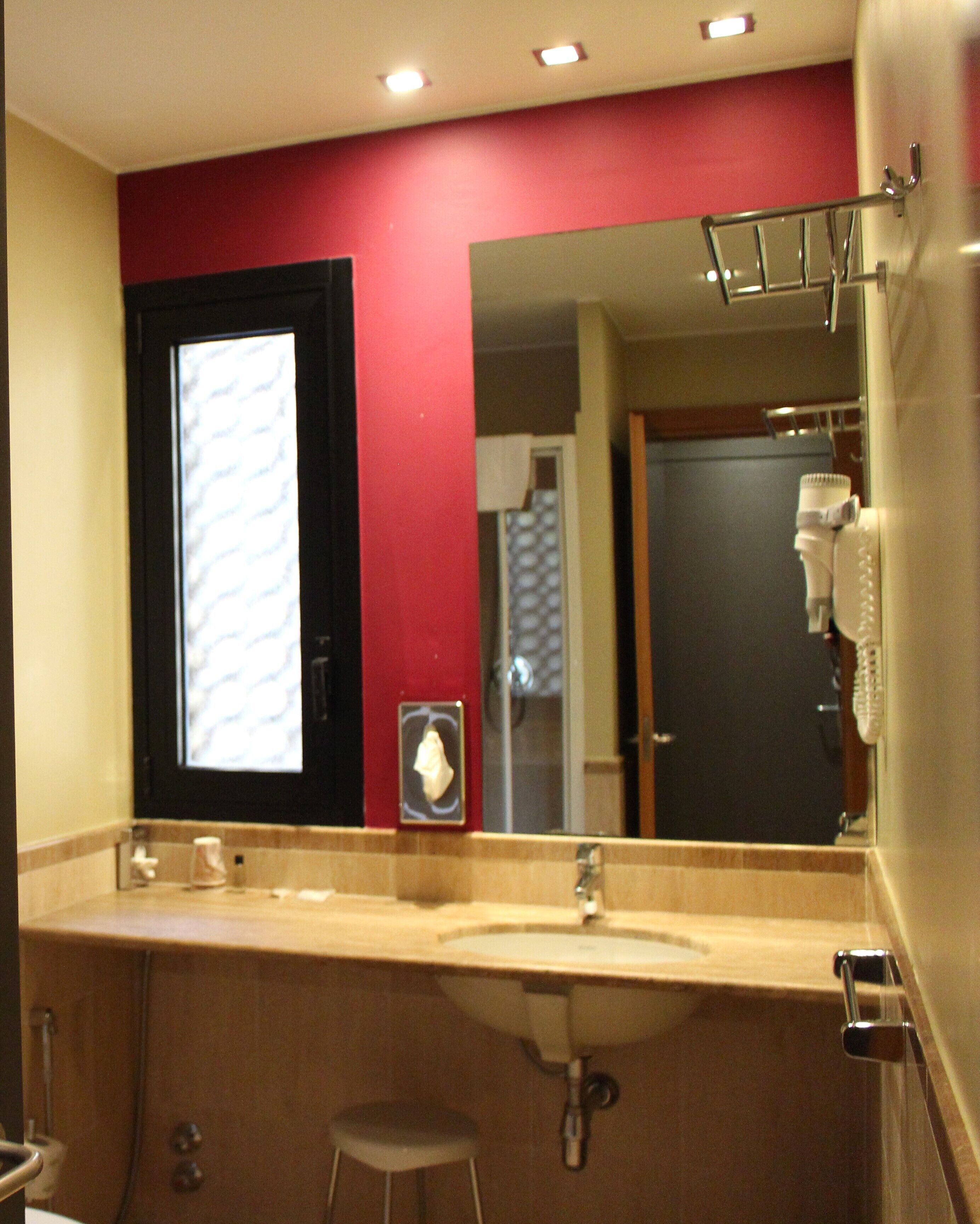Un baño con un lavabo color crema, un espejo, un perchero para toallas y un inodoro.