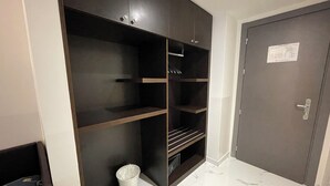 A room with a dark wooden wardrobe, a white trash bin, and a door with a notice on it. - Hotel Club (Milan)