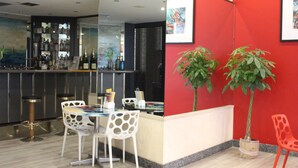 A modern bar area with a counter, white chairs, and two potted plants. - Hotel Club (Milan)