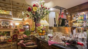 A bar area with a variety of liquor bottles, a fruit bowl, and a floral arrangement. - Hotel Vittoria (Milan)