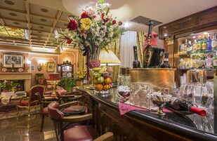 A bar area with a variety of liquor bottles, a fruit bowl, and a floral arrangement.