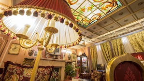 A luxurious room with a large ornate lamp, a fireplace, and a floral stained glass window. - Hotel Vittoria (Milan)