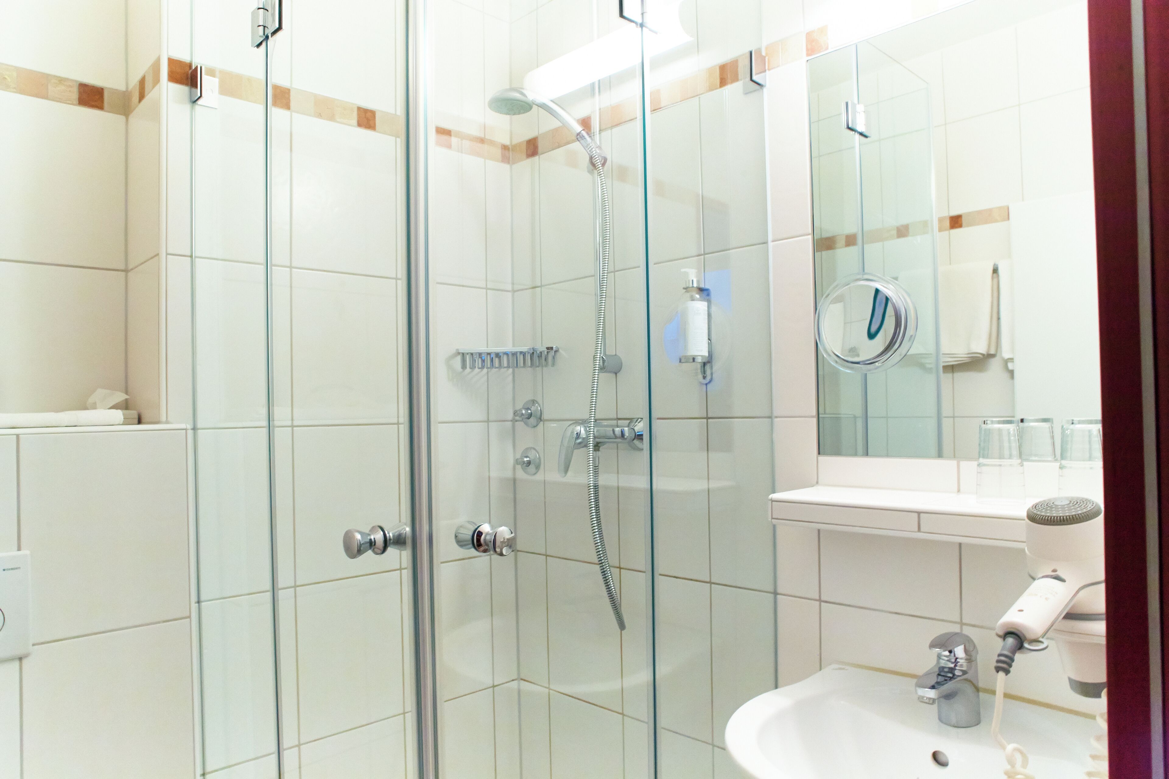 Un baño moderno con ducha de vidrio, lavamanos y espejo.