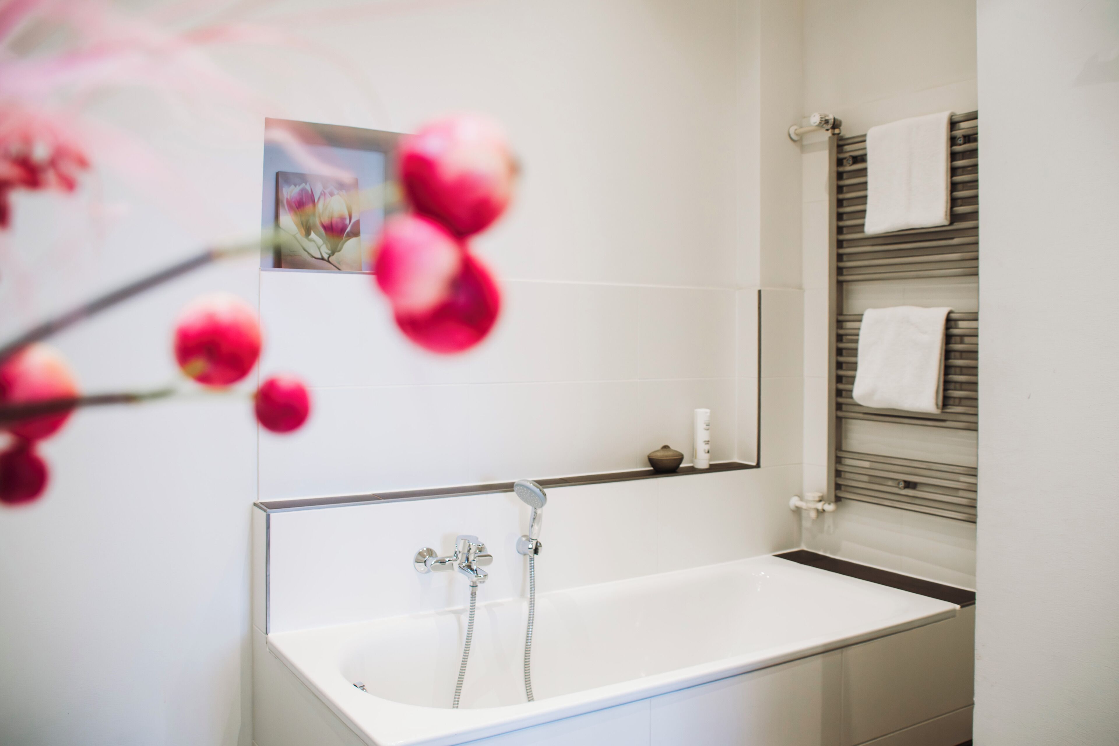 A modern bathroom with a white bathtub, a towel rack, and a small shelf.