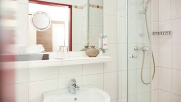Une salle de bain équipée d’un lavabo, d’un miroir, d’une douche et d’un porte-serviettes.
