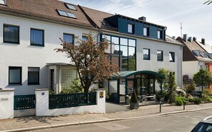 Une rangée de maisons modernes à deux étages, dotées d’un espace extérieur aménagé et couvert, et d’une enseigne indiquant qu’il s’agit d’un hôtel.